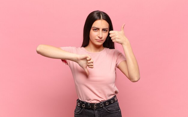 Mulher jovem e bonita se sentindo confusa, sem noção e insegura, avaliando o que há de bom e de ruim em diferentes opções ou escolhas