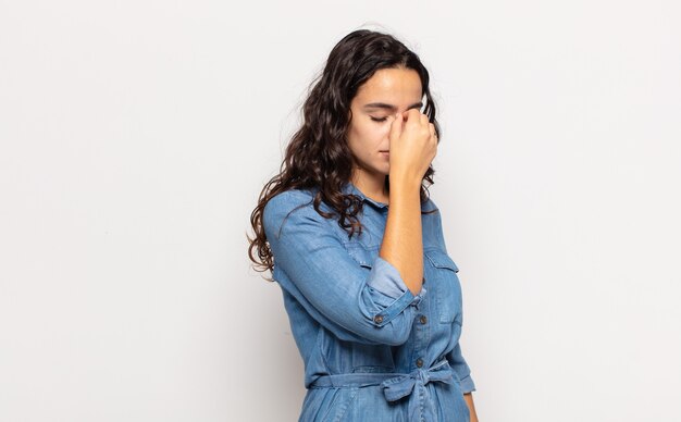 Mulher jovem e bonita se sentindo estressada, infeliz e frustrada, tocando a testa e sofrendo de enxaqueca de forte dor de cabeça