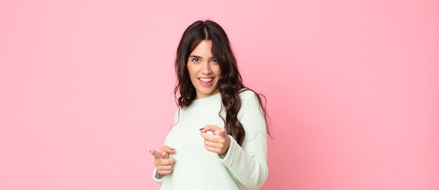 Mulher jovem e bonita se sentindo feliz, descolada, satisfeita, relaxada e bem-sucedida, apontando para a câmera, escolhendo você