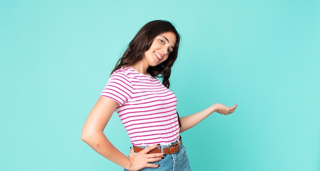 Foto mulher jovem e bonita se sentindo feliz e alegre, sorrindo e dando as boas-vindas a você, convidando-a com um gesto amigável