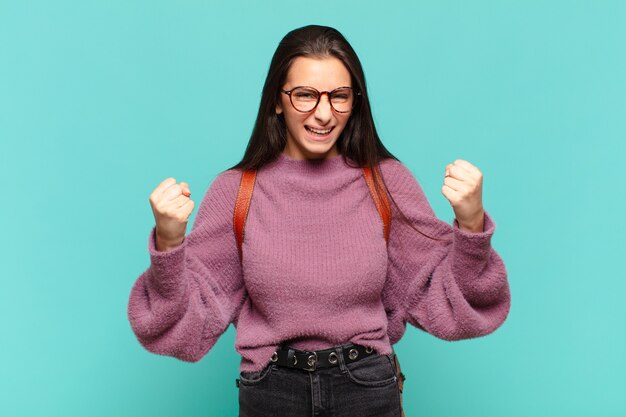 Mulher jovem e bonita se sentindo feliz, surpresa e orgulhosa, gritando e comemorando o sucesso com um grande sorriso.