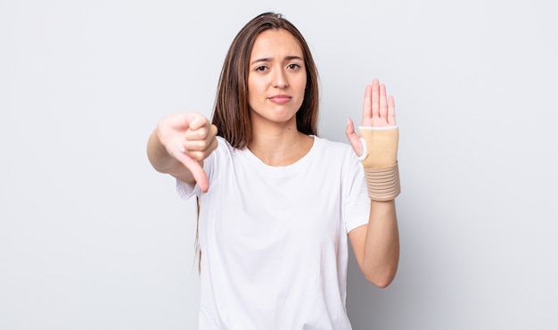 Mulher jovem e bonita se sentindo mal, mostrando os polegares para baixo. conceito de bandagem de mão