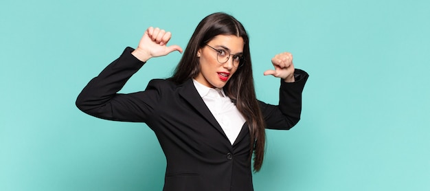 Mulher jovem e bonita se sentindo orgulhosa, arrogante e confiante, parecendo satisfeita e bem-sucedida, apontando para si mesma. conceito de negócios