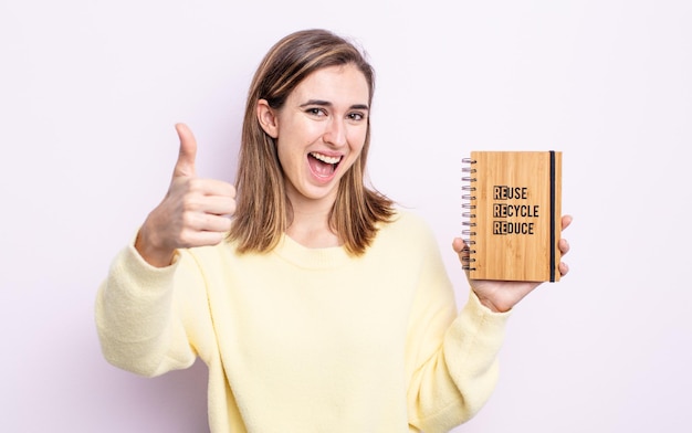 Mulher jovem e bonita se sentindo orgulhosa, sorrindo positivamente com o polegar para cima. conceito de reciclagem