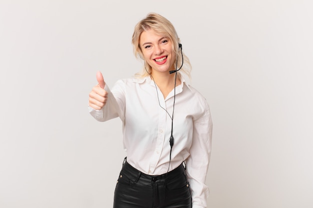 Mulher jovem e bonita se sentindo orgulhosa, sorrindo positivamente com o polegar para cima