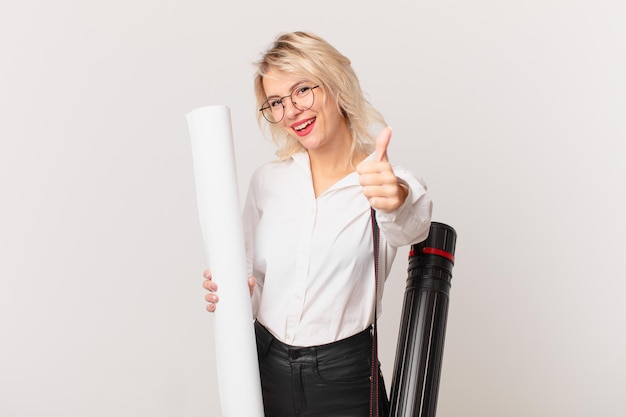 Mulher jovem e bonita se sentindo orgulhosa, sorrindo positivamente com os polegares para cima. conceito de arquiteto