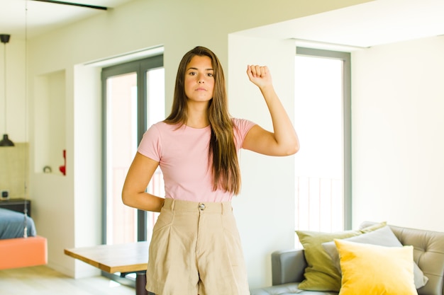 Mulher jovem e bonita se sentindo séria, forte e rebelde, levantando o punho, protestando ou lutando pela revolução