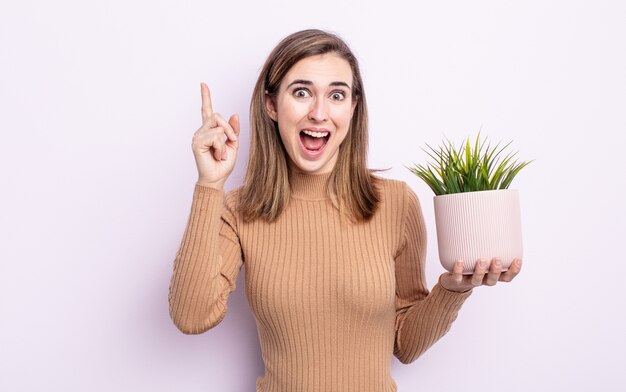 Mulher jovem e bonita se sentindo um gênio feliz e animado depois de perceber uma ideia. conceito de planta