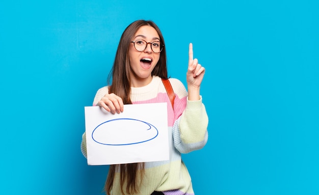 Mulher jovem e bonita se sentindo um gênio feliz e animado depois de realizar uma ideia, levantando o dedo alegremente, eureka!