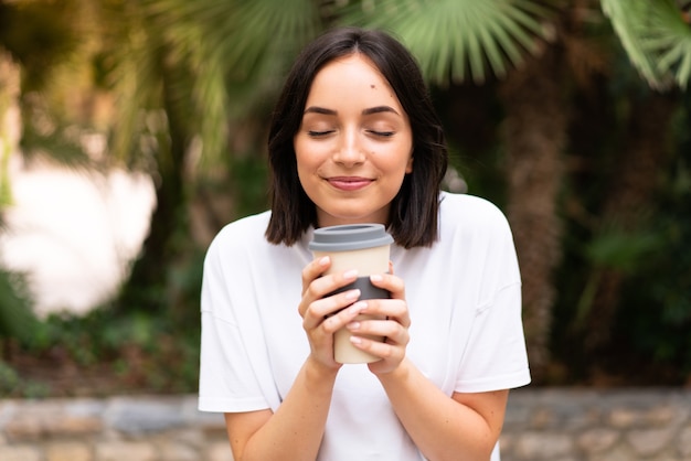 Mulher jovem e bonita segurando café para levar ao ar livre