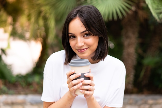 Mulher jovem e bonita segurando café para levar ao ar livre