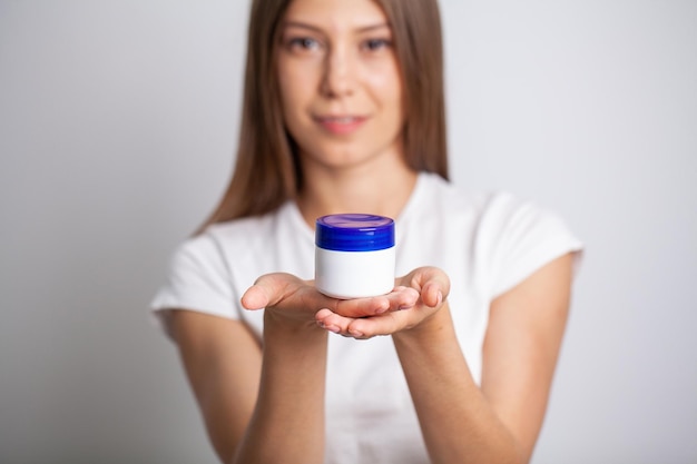 Mulher jovem e bonita segurando creme hidratante nas mãos