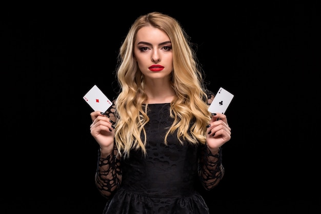 Mulher jovem e bonita segurando dois ás de cartas na mão, isolado no fundo preto