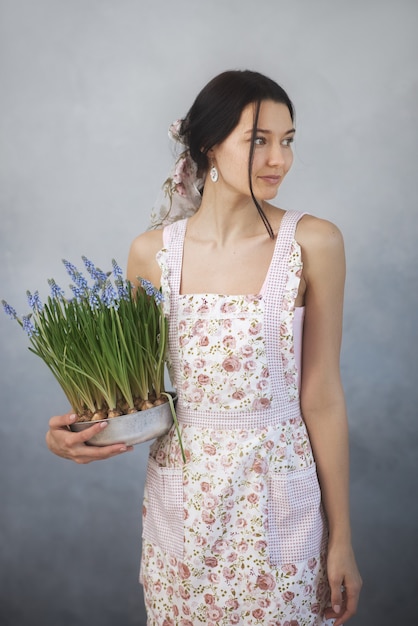 Mulher jovem e bonita segurando flores da primavera em um vaso