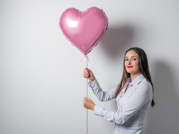 Mulher jovem e bonita segurando um balão de ar em forma de coração