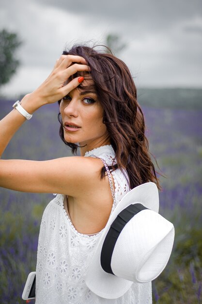 mulher jovem e bonita sensual com chapéu e vestido branco no campo de lavanda