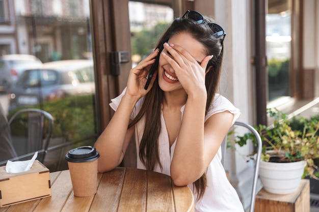 Mulher jovem e bonita sentada à mesa do café ao ar livre