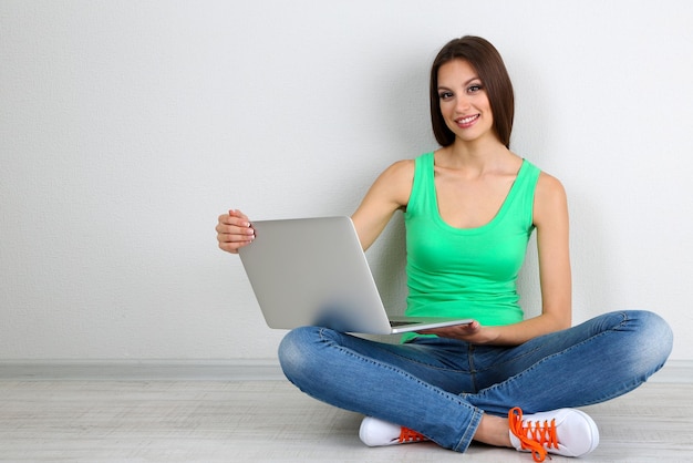 Mulher jovem e bonita sentada com o laptop na sala