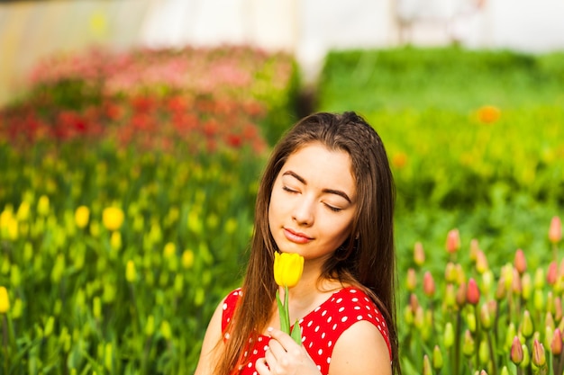 Mulher jovem e bonita sentada em um campo de tulipas ao pôr do sol