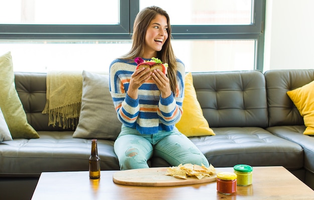 Mulher jovem e bonita sentada em um sofá de couro comendo