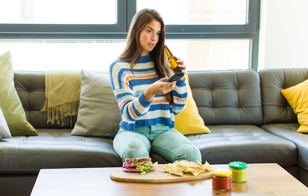 Mulher jovem e bonita sentada em um sofá de couro comendo