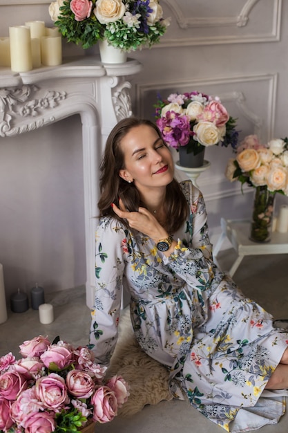 Mulher jovem e bonita sentada em uma sala entre as flores