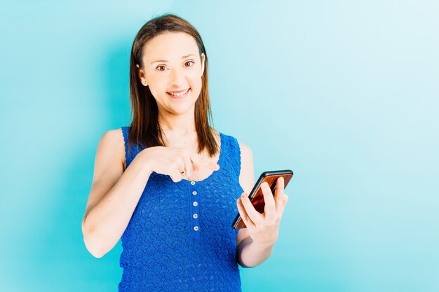 Mulher jovem e bonita sorridente apontando para o smartphone. conceito de tecnologia