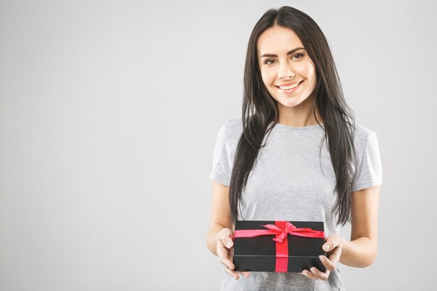 Mulher jovem e bonita sorridente segurando uma caixa de presente preta