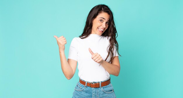 Mulher jovem e bonita sorrindo alegremente e casualmente apontando para copiar o espaço ao lado, sentindo-se feliz e satisfeita