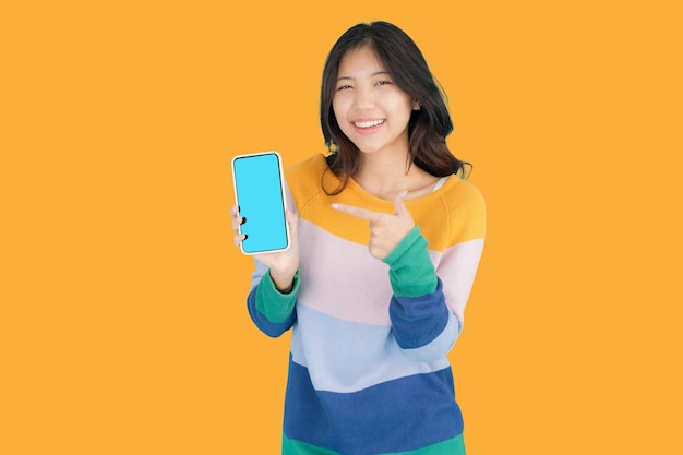 Foto mulher jovem e bonita sorrindo alegremente enquanto segura um smartphone na mão