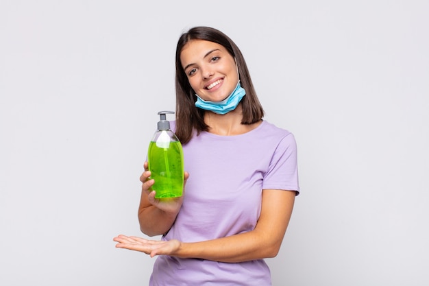 Mulher jovem e bonita sorrindo alegremente, se sentindo feliz e mostrando um conceito no espaço da cópia com a palma da mão