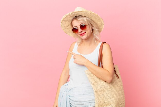 Mulher jovem e bonita sorrindo alegremente, sentindo-se feliz e apontando para o lado. conceito de turista de verão