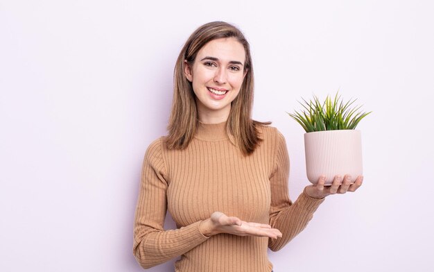 Mulher jovem e bonita sorrindo alegremente, sentindo-se feliz e mostrando um conceito. conceito de planta