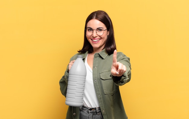 Foto mulher jovem e bonita sorrindo com orgulho e confiança fazendo a pose número um triunfantemente, sentindo-se uma líder