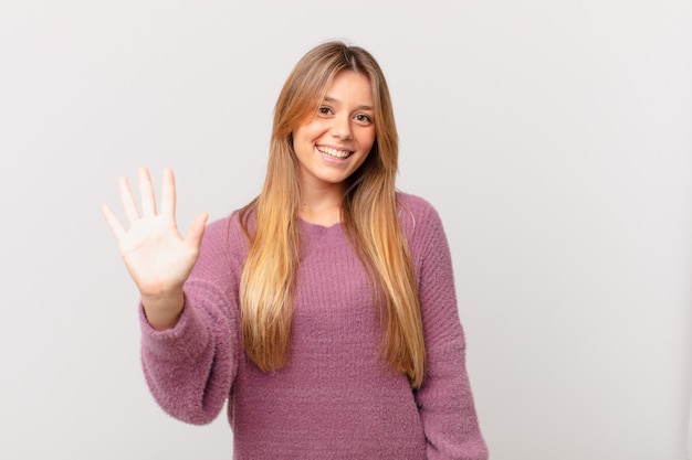 Mulher jovem e bonita sorrindo e parecendo amigável, mostrando o número cinco