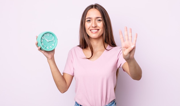 Mulher jovem e bonita sorrindo e parecendo amigável, mostrando o número quatro. conceito de despertador