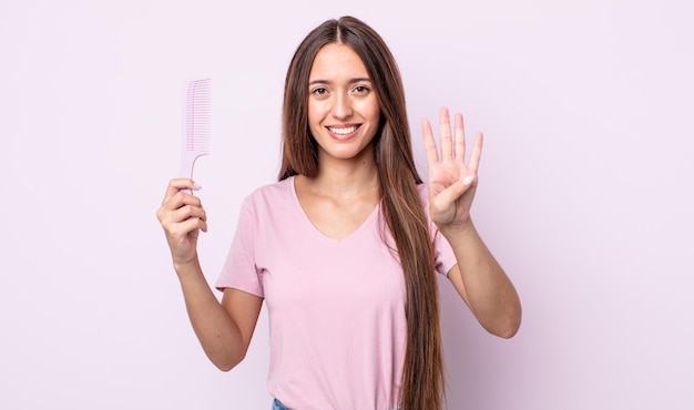 Mulher jovem e bonita sorrindo e parecendo amigável, mostrando o número quatro. conceito de pente de cabelo