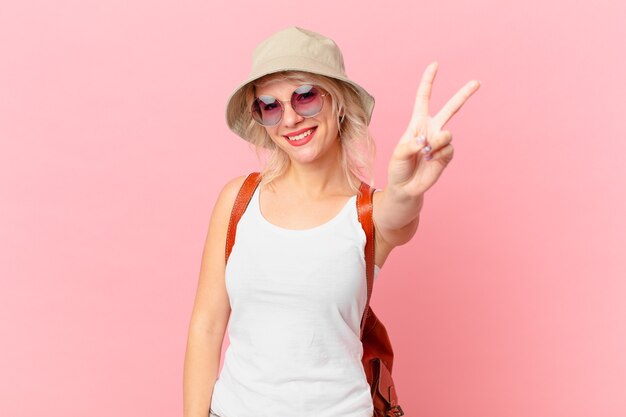 Mulher jovem e bonita sorrindo e parecendo feliz, gesticulando vitória ou paz