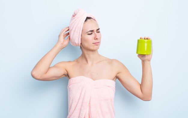 Mulher jovem e bonita sorrindo feliz e sonhando acordada ou duvidando. conceito de produto para banho e cabelo