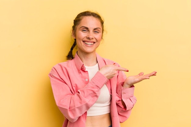 Mulher jovem e bonita sorrindo, sentindo-se feliz, despreocupada e satisfeita, apontando para o conceito ou ideia no espaço da cópia ao lado