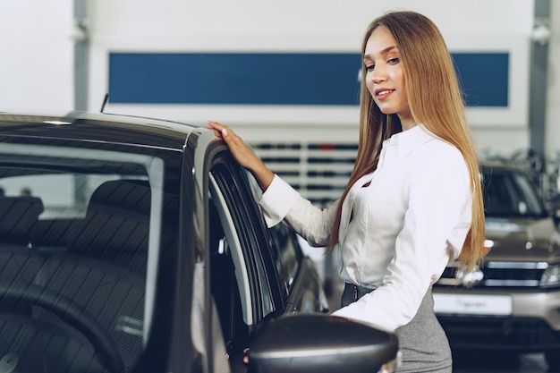 Mulher jovem e bonita tocando seu novo carro com prazer e alegria