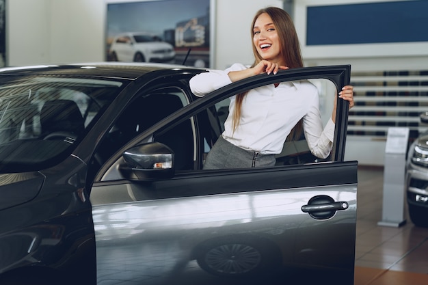 Foto mulher jovem e bonita tocando seu novo carro com prazer