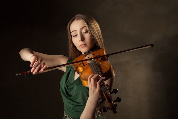 Mulher jovem e bonita tocando violino sobre fundo preto