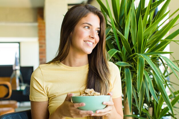 Mulher jovem e bonita tomando café da manhã em casa