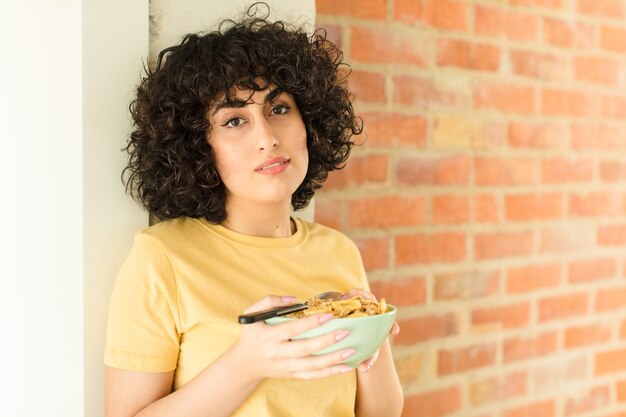 Mulher jovem e bonita tomando café da manhã em casa