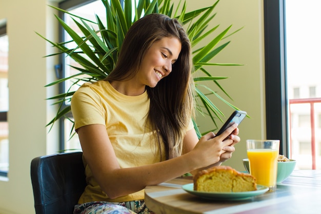 Mulher jovem e bonita tomando café da manhã em casa