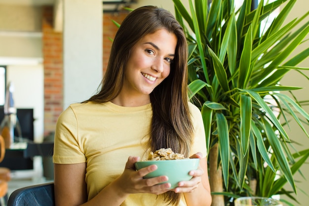 Mulher jovem e bonita tomando café da manhã em casa