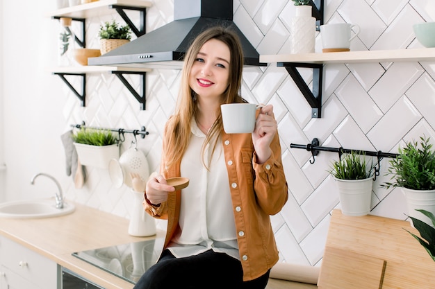 Mulher jovem e bonita tomando café na cozinha