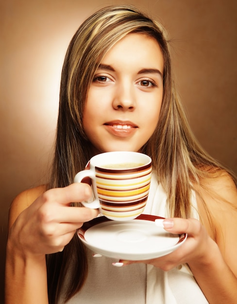 Mulher jovem e bonita tomando café sobre fundo bege