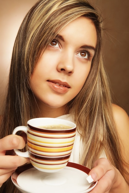 Foto mulher jovem e bonita tomando café sobre fundo bege